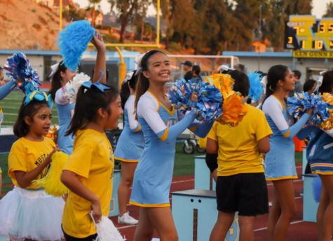 Varsity junior Stella Lim performs a cheer during the first quarter with young cheerleaders who participated at the Junior Cheer Camp. I am super excited that I got to help teach girls how to cheerlead, Lim said. 