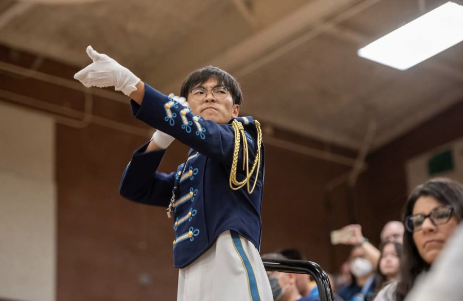 Bring the thunder | Assistant drum major senior Anthony Chae conducts the field show from the competition stands. I was focused on trying to convey what I wanted the band to do at that moment, Chae said. It suddenly rained, so [the drum majors] had to make different plans and conduct in the bleachers, but it was a really cool experience. 