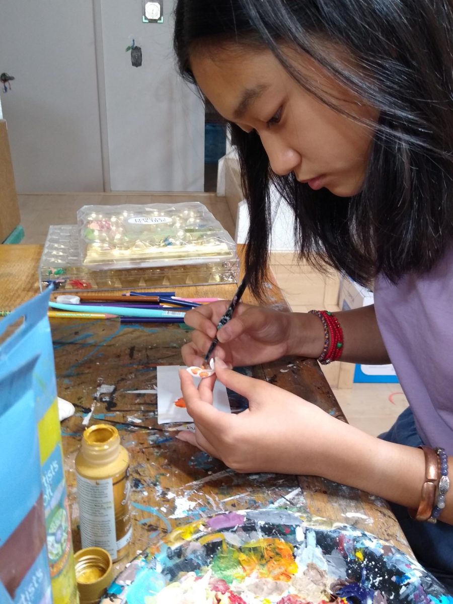 Freshman Vivian Chen paints a koi fish for one of her commissions. 