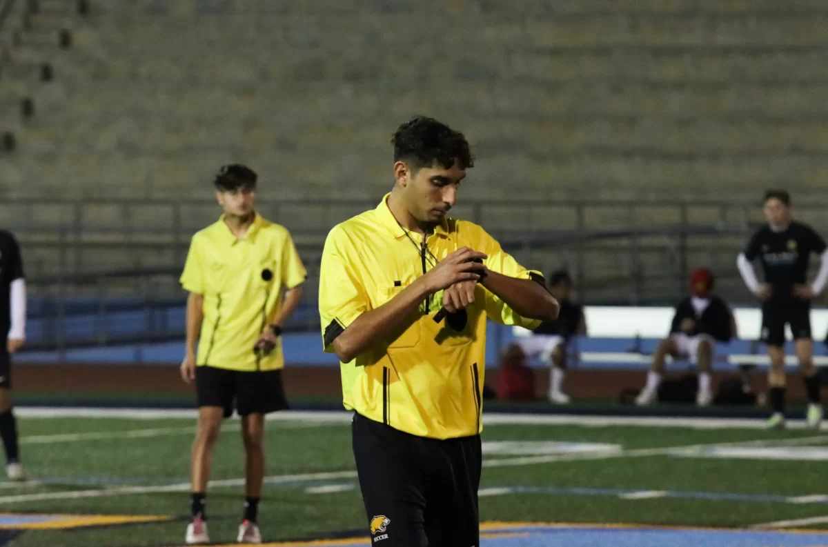A soccer referee checks the remaining time in the first half at the varsity boys soccer game against Ruben S. on Dec. 4
