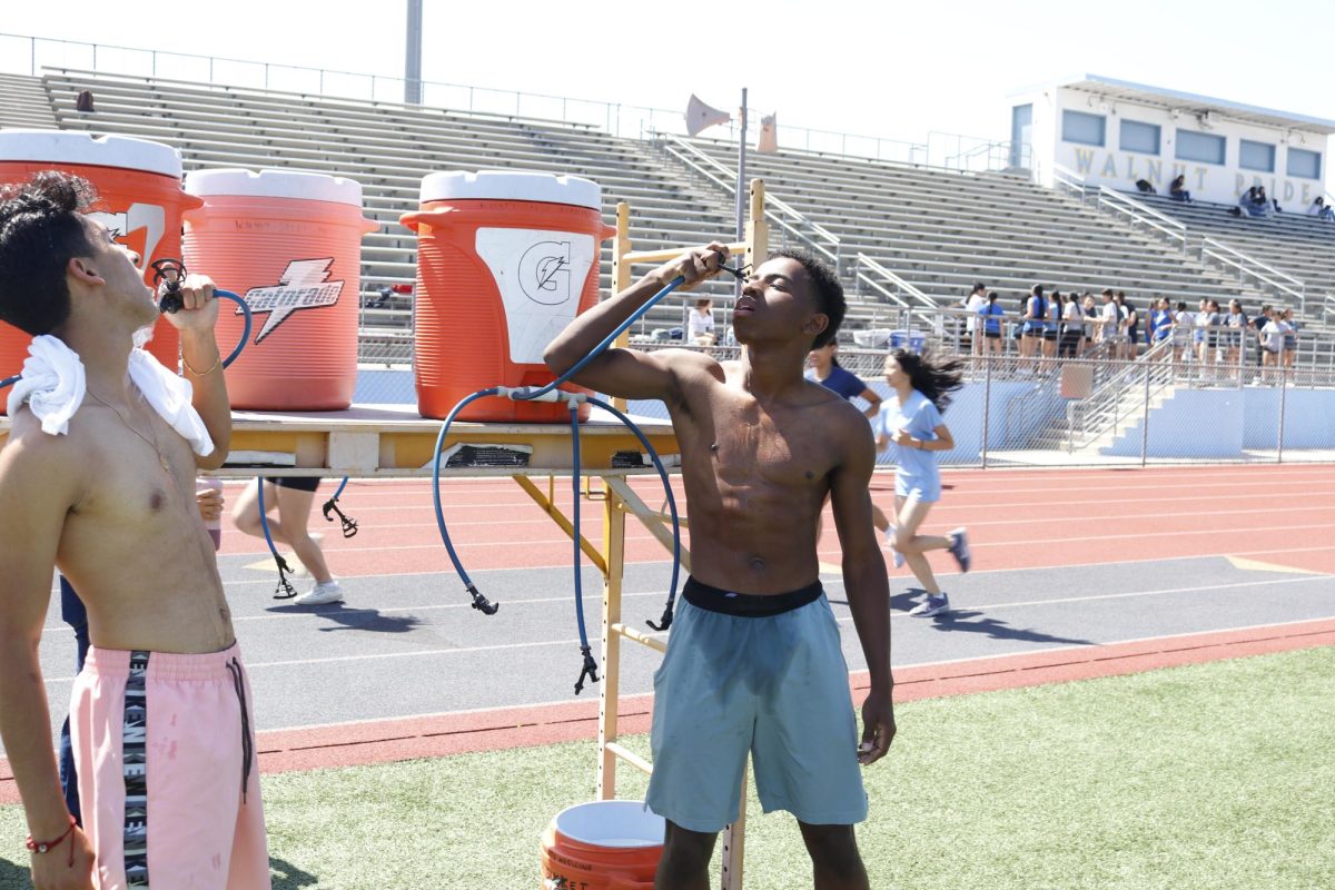 Senior Jonathan Crawford finishes his running routine and cools off by the water station. “It was a long day of [track] practice and we just finished running 350 meters and then sprinting 50 meters,” Crawford said. “It was hot and I was exhausted after the long day.” 