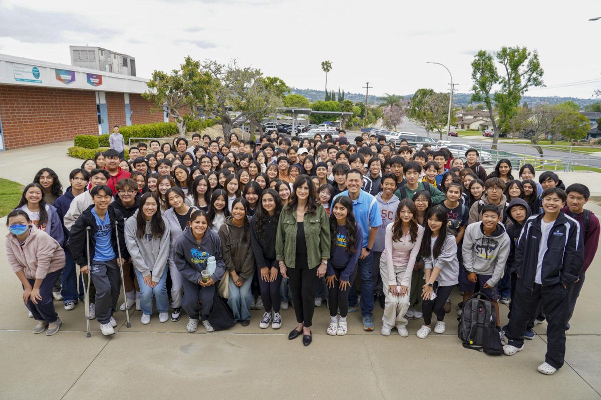 Students gather behind English teacher Lisa Donee (center) to acknowledge her influence as their teacher. Retiring this year, Donee has impacted generations of students. From alumni like chemistry teacher Garrett Lim (center right) to his son, freshman Lucas Lim (far right), and siblings or parents of current students, she will be missed by many people at Walnut High School. 