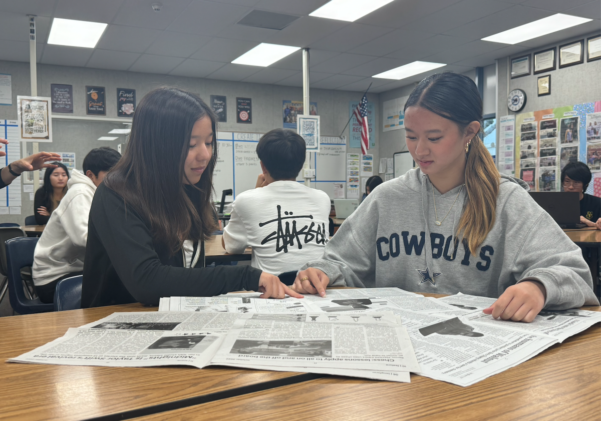 Freshmen staffers Taryn Schilz (left) and Lydia Wang (right) look through past newspapers to get inspiration for their stories.  “Being in youth journalism, you’re able to feel more connected to other students in different extracurriculars,” Schilz said.