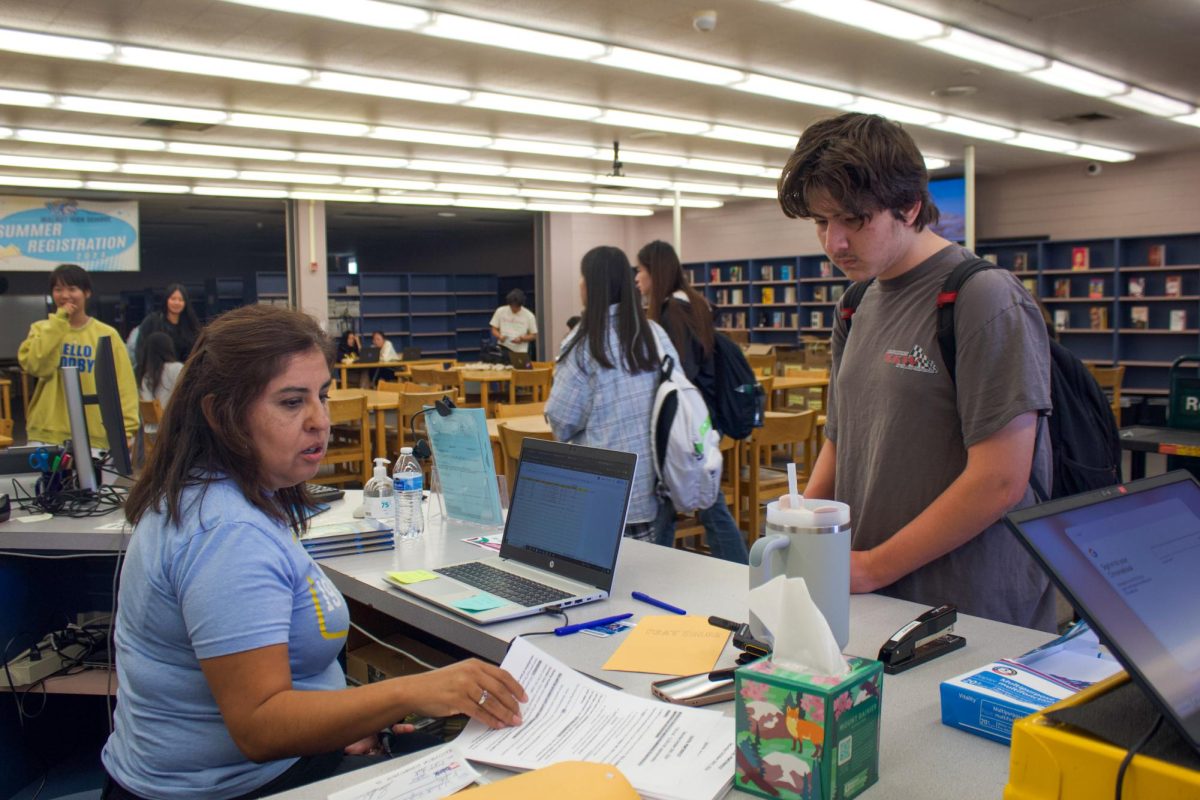 PSAT sales | Grade level coordinator Jenny Alegre sells a PSAT to sophomore Charles Dunn. “I was kind of nervous because now I have to prepare for this test. I’m going to have to spend a lot of time at home studying and making sure I’m prepared for the test,” Dunn said.  