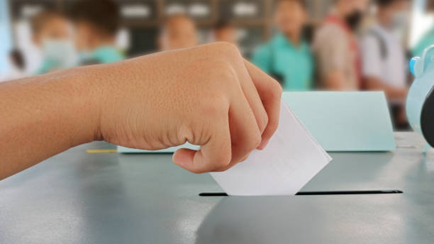 Students hand in their paper vote for an election. 