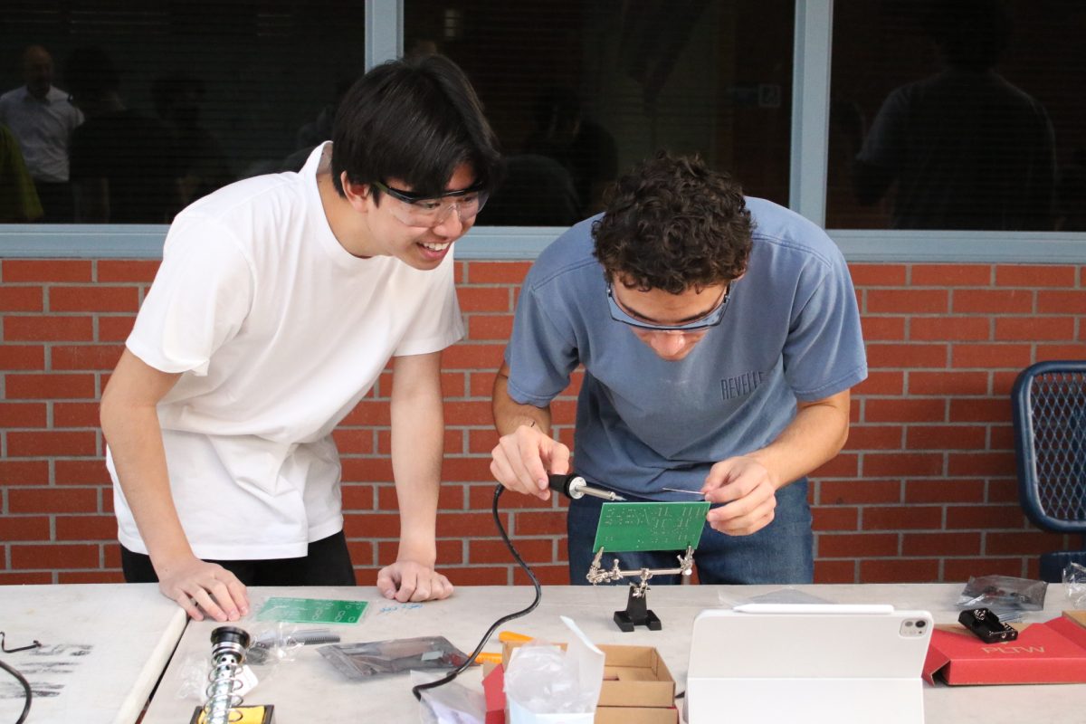 Seniors Joseph Chua and Ibi Hajar solder circuits to the board. 