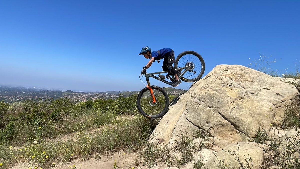 Freshman Caleb Cheng rides his mountain bike down a steep rock. 