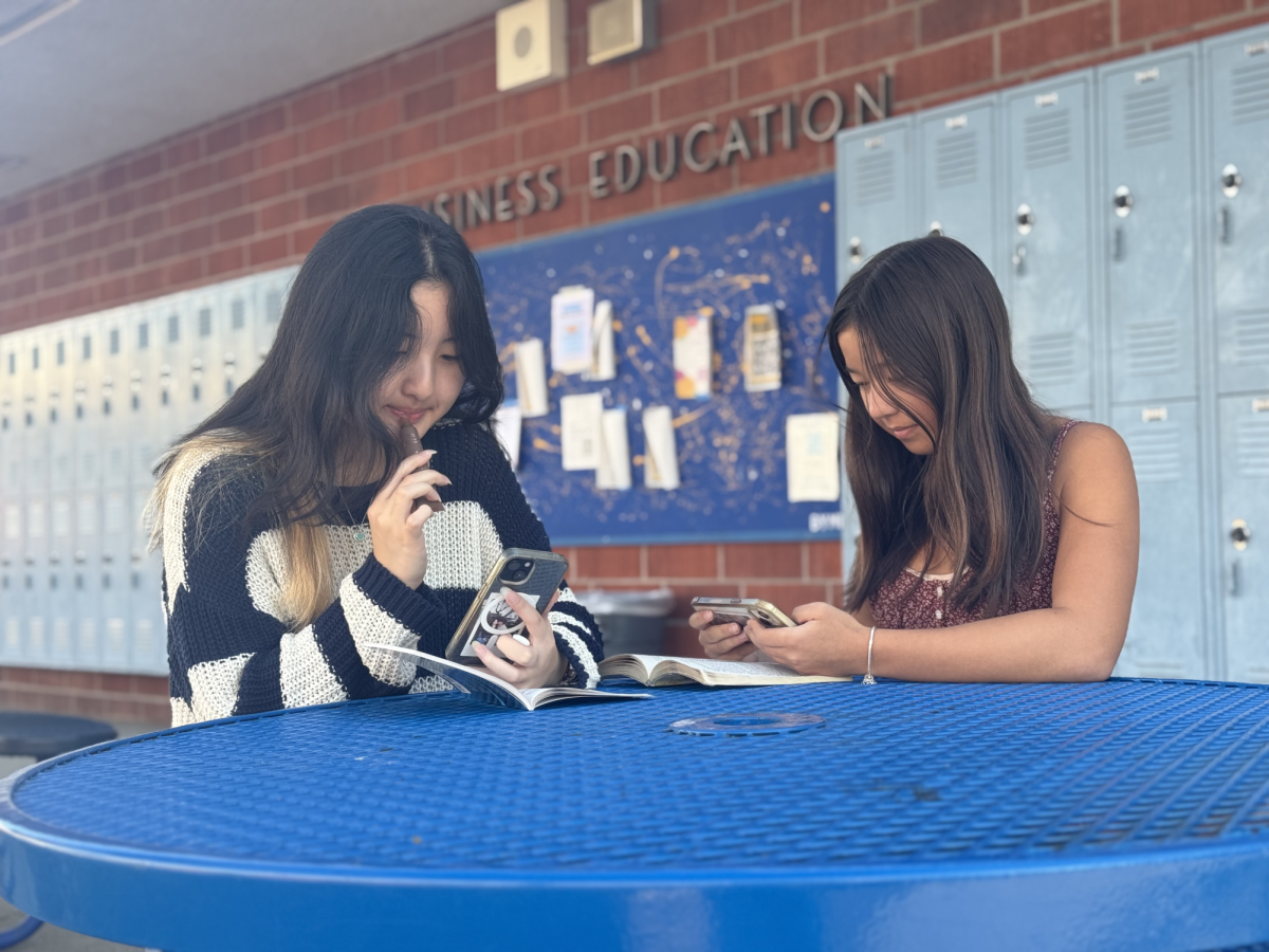 Junior Rylyn Wang and sophomore Taryn Schilz scroll on their phones, procrastinating on their homework. 