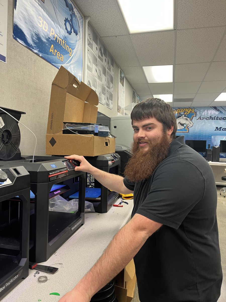 Industrial design teacher Kyle Kinne operates his Makerbot 3D printer in his classroom. “The 3D printer helps with my projects because it is very easy to produce working parts and prototypes,” Kinne said.