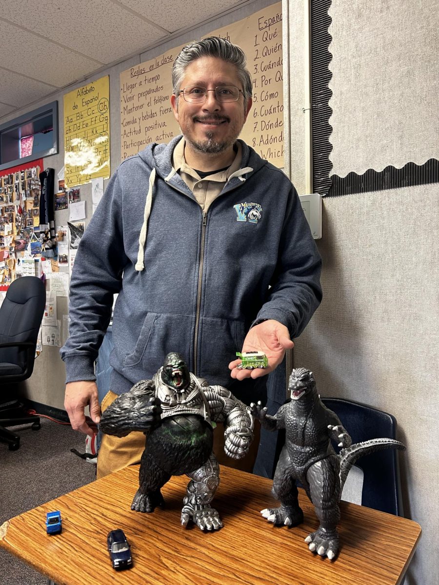 Spanish teacher Gabriel Hernandez poses with some of the items he’s thrifted: a Godzilla and King Kong figure along with vintage car toys. “The Godzilla and King Kong, they represent my childhood because I saw the movies and they remind me of when I was younger,” Hernandez said.