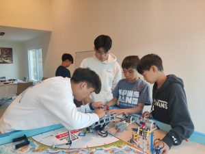 Seniors Dylan Thai and Harry Zhang help middle schoolers construct a machine. 