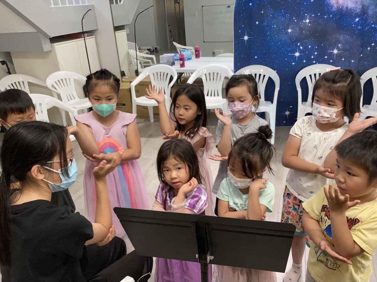 Chamber Choir senior Jacqueline Luo guides a young group of students through music. 