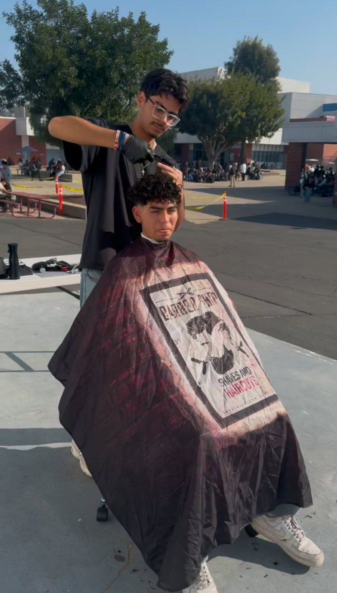 Senior Jonathan Hernandez cuts his cousin, junior Christian Chavez’s hair on the stage during lunch. “It felt exhilarating to me. I had never done anything like that before and I remember people asking me if I could cut their hair after lunch,” Hernandez said. “I got my cousin to be the model because he was the first ever customer I had.”