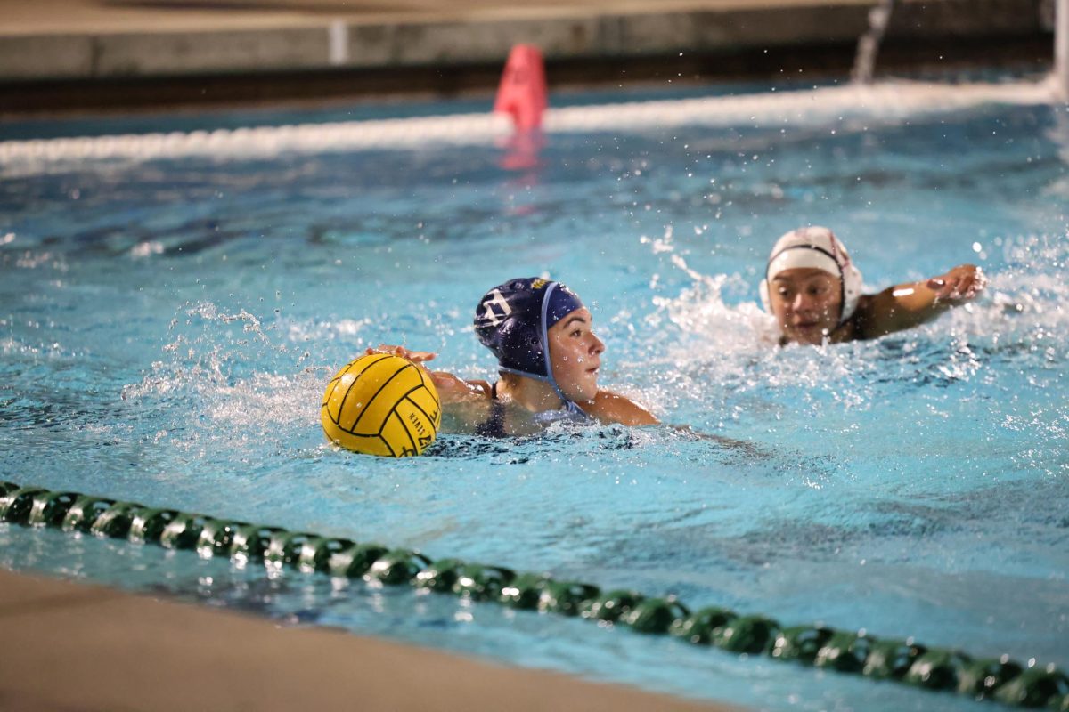 Scanning the pool |  1/2 attacker junior Emma Roarick looks to make a play toward the goal in a 5-4 CIF first round win over Patriot. “I was feeling very nervous for this game because we played this team already and won by only one point last time. The game was nerve-wracking, and we had a lot of challenges that game. It was a very good game, and we put up a really good fight. It was exciting to win that game, especially for it being our first [CIF] game this season,” Roarick said. 