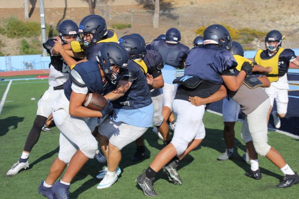 The boys football team runs a play in an after-school practice. 
