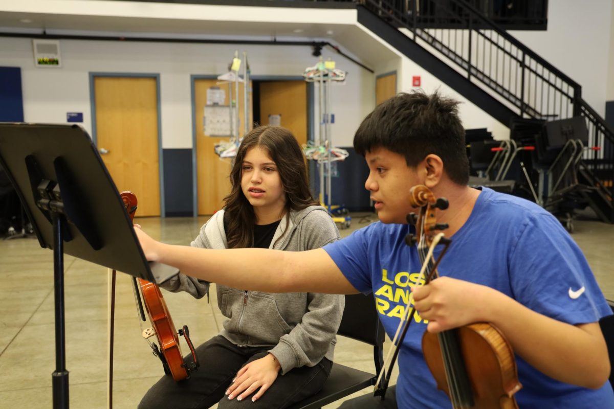 Music mentor | Violinist junior Lucas Villareal helps guide freshman Sophia Coreas. “I think it’s a really good opportunity to teach [the underclassmen] not only skills when it comes to music, but also passions,” Villareal said.” 