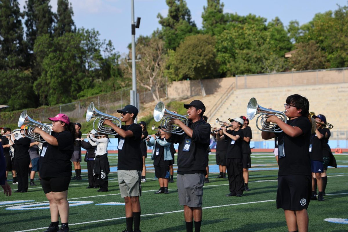 From left to right, seniors Thinon Halgama and section leader Oscar Francia practice “Cosmic Codes” before a football game. “I was playing together with my section and enjoying the mood of the music,” Francia said.