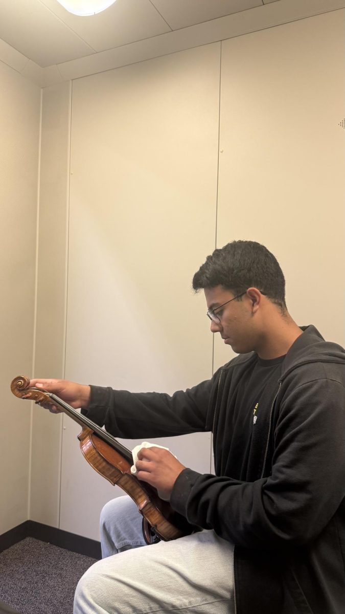 Senior Gabriel Gonzalez tunes his violin in a orchestra practice room.