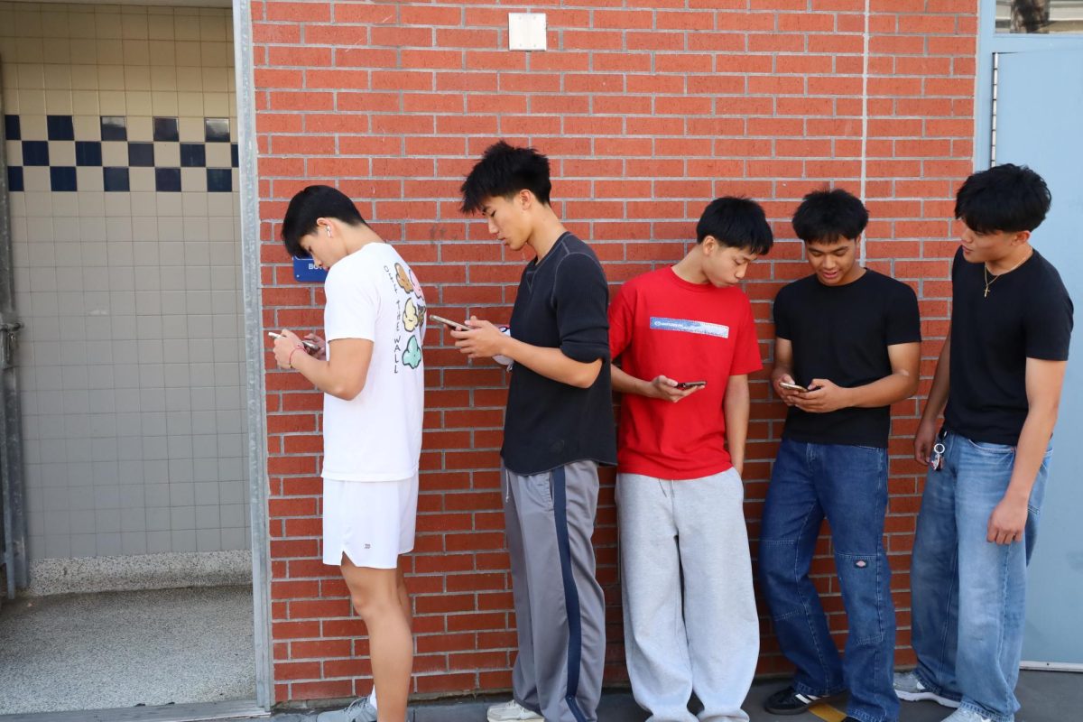 Students wait outside the Z-building restroom as new rules limit entry. Some find the wait frustrating, while others support the change for reducing vaping and odor.