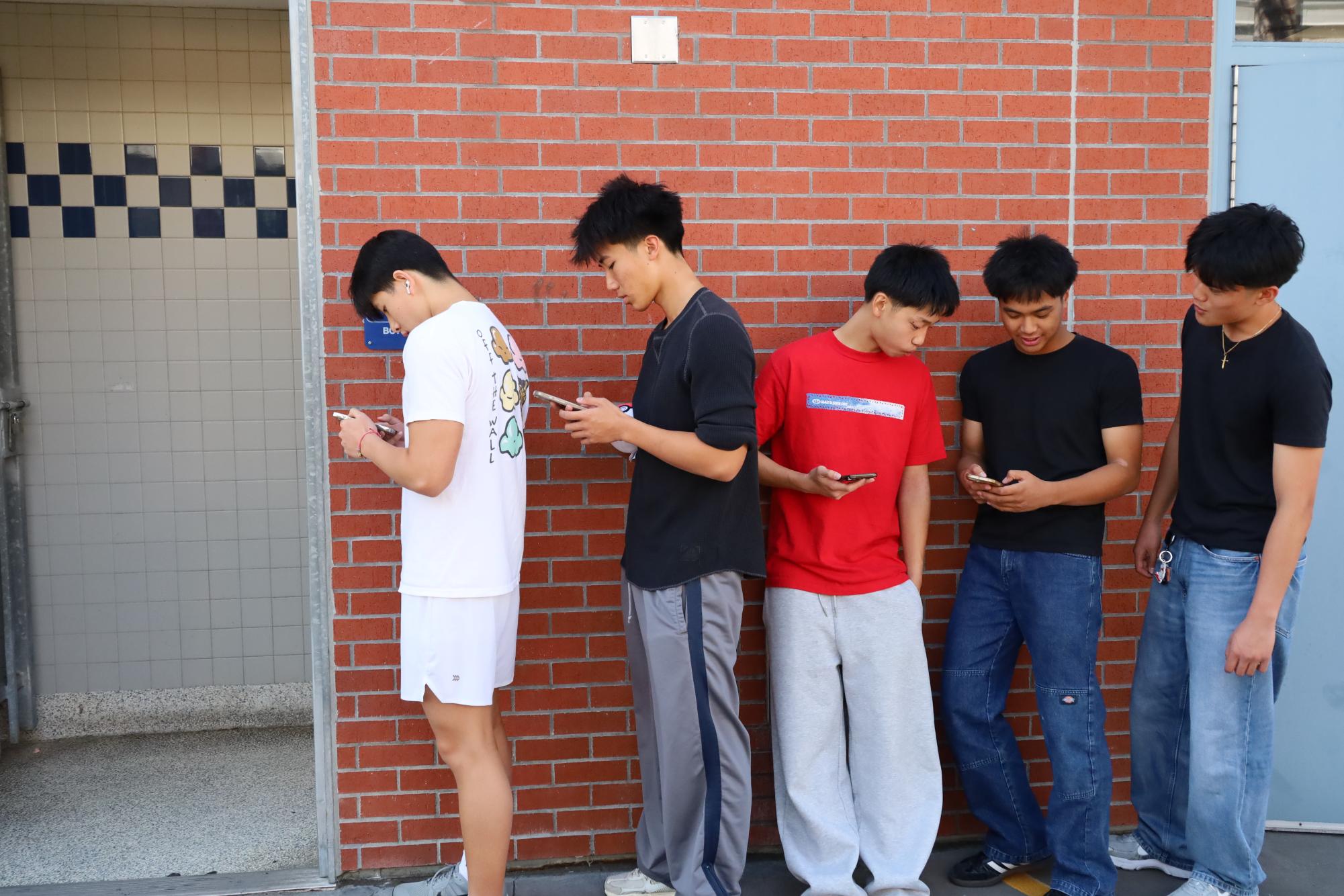 Students wait outside the Z-building restroom as new rules limit entry. Some find the wait frustrating, while others support the change for reducing vaping and odor.