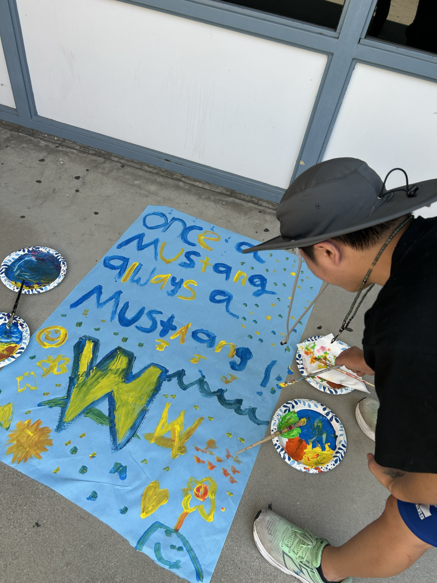 Senior Evan Chang paints a poster for Branding Iron.