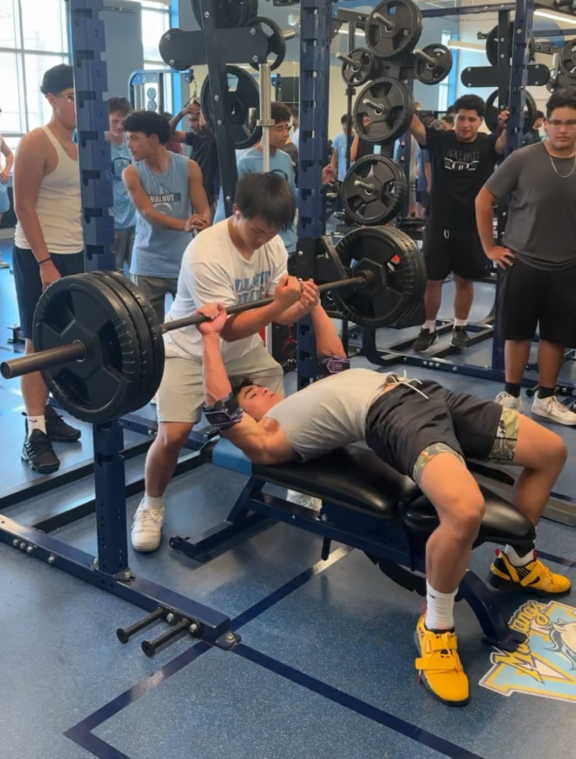 Senior Jonah Lin practices lifting in the weight room with the support of his teammates.