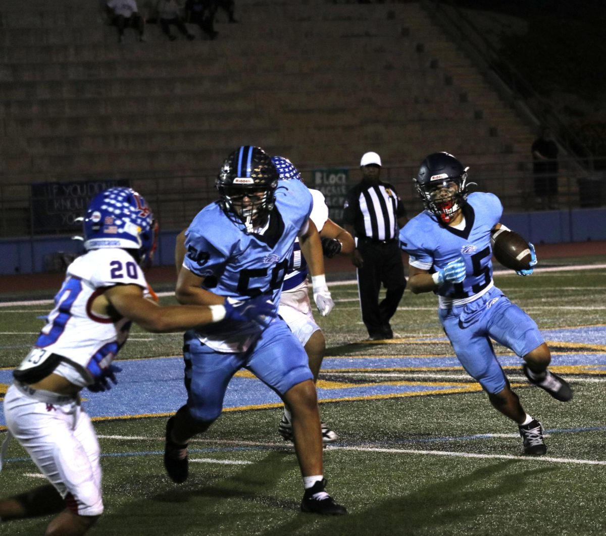 A Mustang player running a play while his teammate is on defense with the opponent.