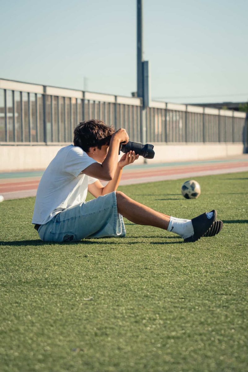 Junior Joaquin Sanchez sits on the turf, capturing a soccer game through his lens.