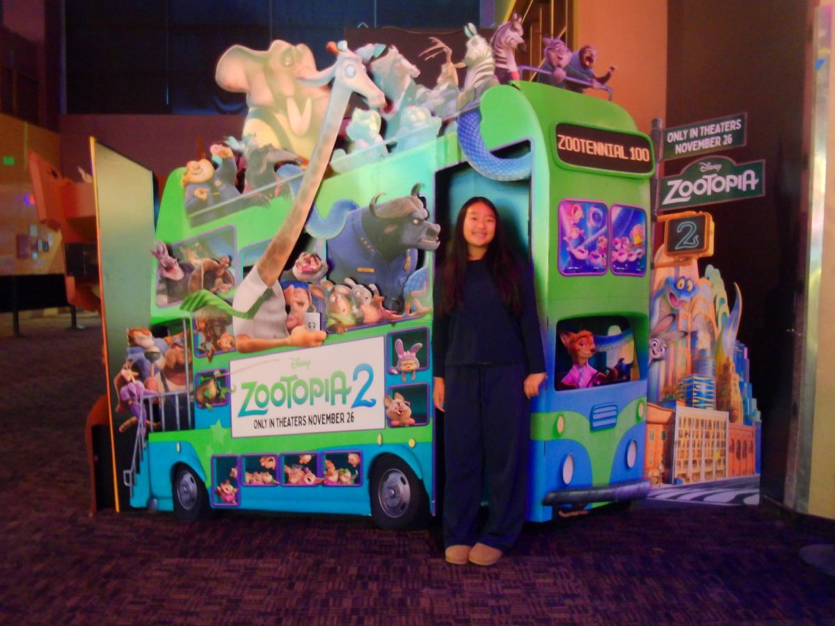 Zoo-on-Top-ia 2 | Staff writer Claire Chen takes a picture with the promotional photo display for “Zootopia 2.”
