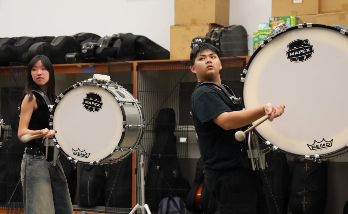 Drumming to the rhythm | From left to right, bass drums sophomore Liz Lee and junior Nathan Chan run through their warm-ups during Winter Percussion rehearsal. “We [usually] play whatever section our [percussion coach] Nate tells us to do and then he’ll give us comments and feedback. He lets us think about our rep and soak in whatever we’ve done,” Chan said.
