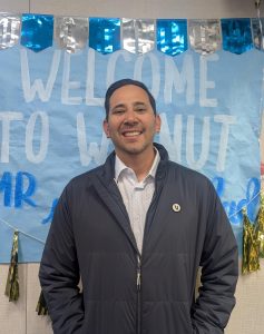 Interim assistant principal Marc Natividad stands in front of his welcome banner.